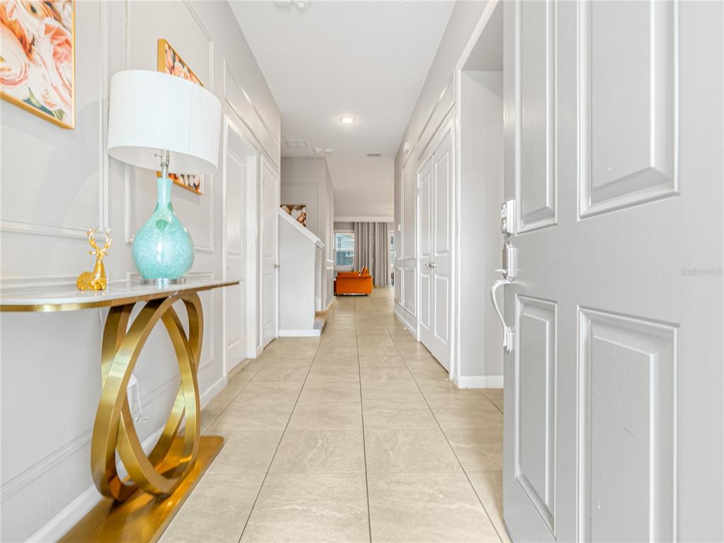 A bright entryway features a gold console table, a turquoise lamp, and light tile flooring — 4451 MONADO DRIVE, KISSIMMEE, FL