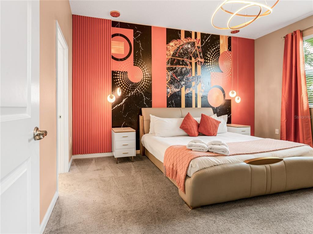 A bedroom features a bed against a wall with coral fluted panels and graphic art — 4451 MONADO DRIVE, KISSIMMEE, FL