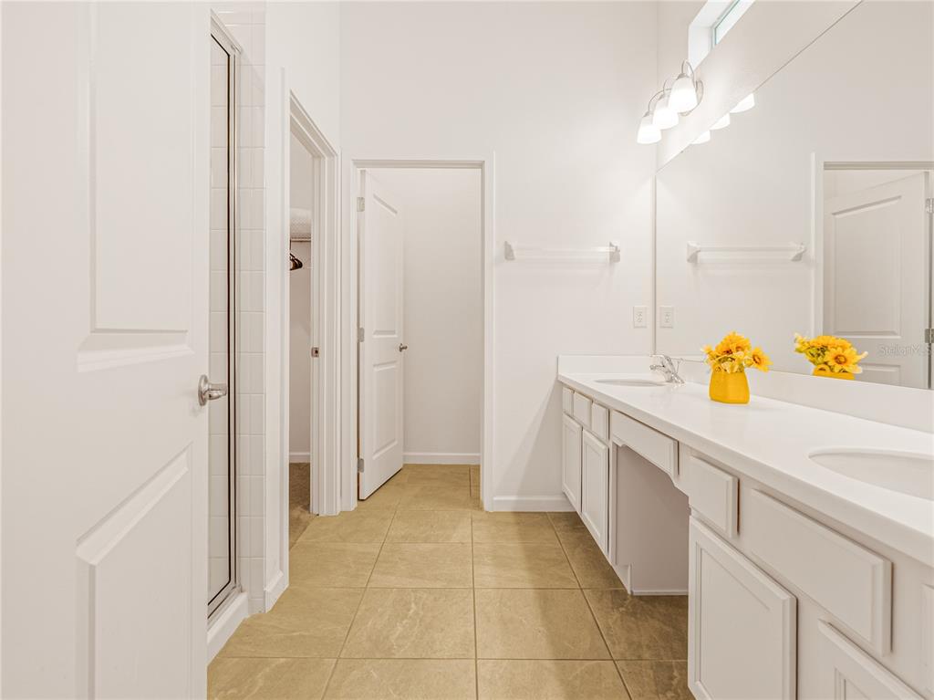 A bathroom features white cabinets, a double vanity, a tiled floor, and a walk-in shower — 4451 MONADO DRIVE, KISSIMMEE, FL