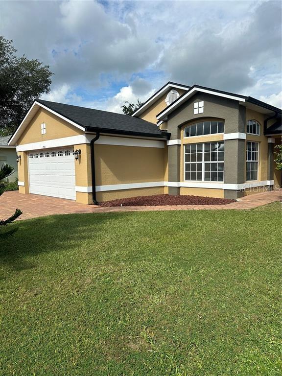 A tan and gray single-story house features a two-car garage and a paved driveway — 2986 STILLWATER DRIVE, KISSIMMEE, FL