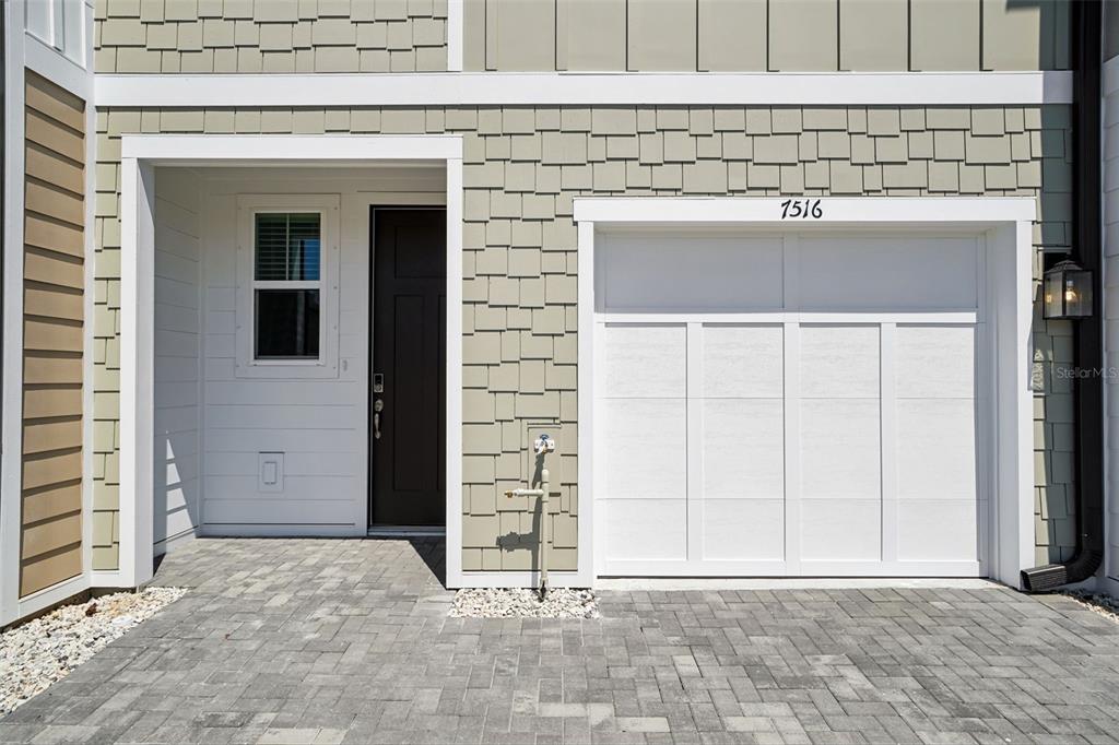 A residential exterior features a paved driveway, a single-car garage, and a dark front door — 7556 DEER VALLEY CIRCLE, TAMPA, FL