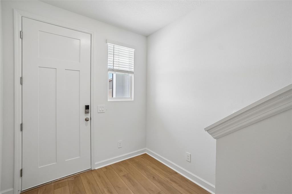 An entryway features a white door, a small window with blinds, and light wood flooring — 7556 DEER VALLEY CIRCLE, TAMPA, FL