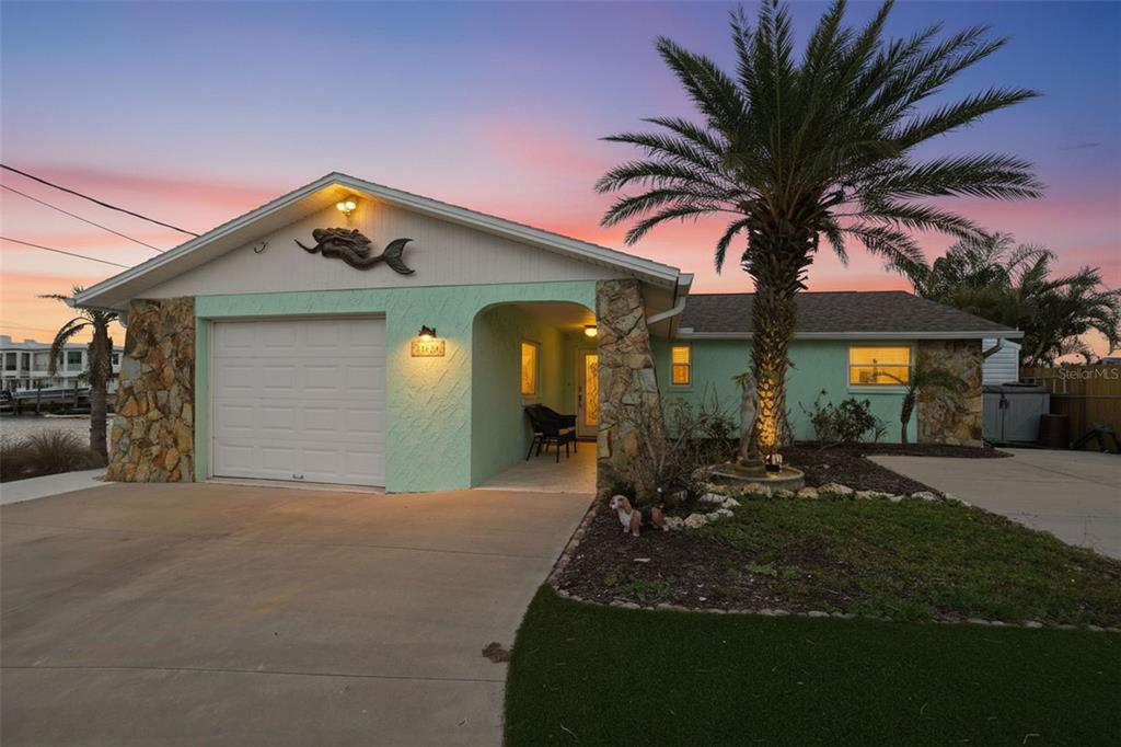 A single-story house with a mint green exterior, stone accents, and a palm tree — 13822 MALCOLM AVENUE, HUDSON, FL