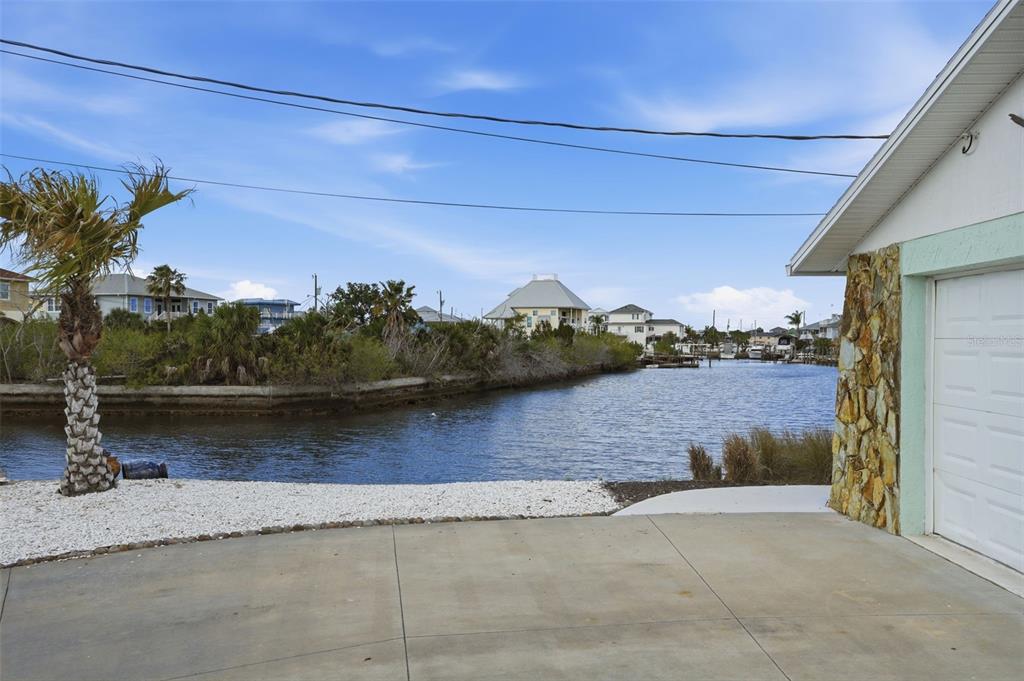 A view of a canal from a concrete driveway next to a house garage — 13822 MALCOLM AVENUE, HUDSON, FL