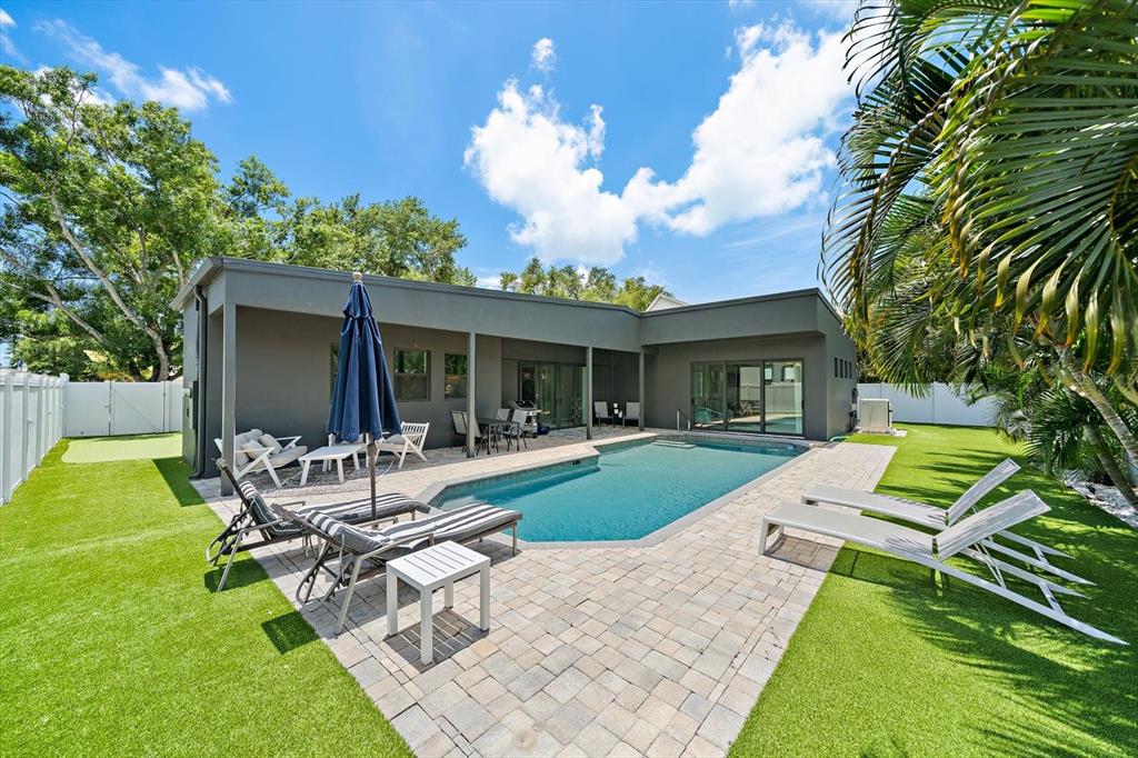 A modern house exterior features a swimming pool, patio furniture, and a green lawn — 1905 TULIP DRIVE, SARASOTA, FL