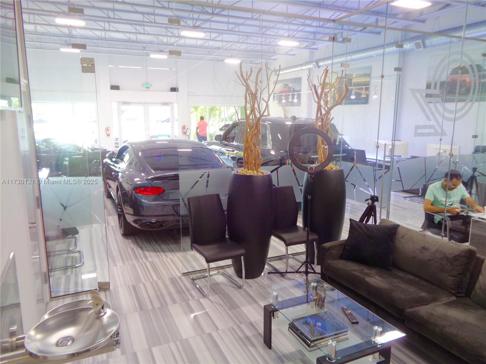 A modern office space features a luxury car, seating area, and glass partitions — 3749 N Federal Hwy, Pompano Beach FL 33064, POMPANO BEACH, FL