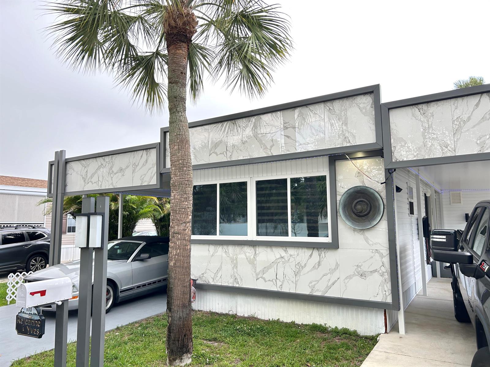 A mobile home exterior features white marble-patterned panels, dark gray trim, and a palm tree — 111 Alamanda Lane, Deerfield Beach FL 33442, DEERFIELD BEACH, FL