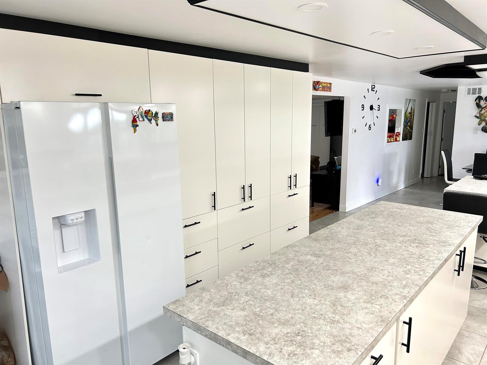 A modern kitchen features white cabinetry, a gray stone-look island countertop, and black hardware — 111 Alamanda Lane, Deerfield Beach FL 33442, DEERFIELD BEACH, FL