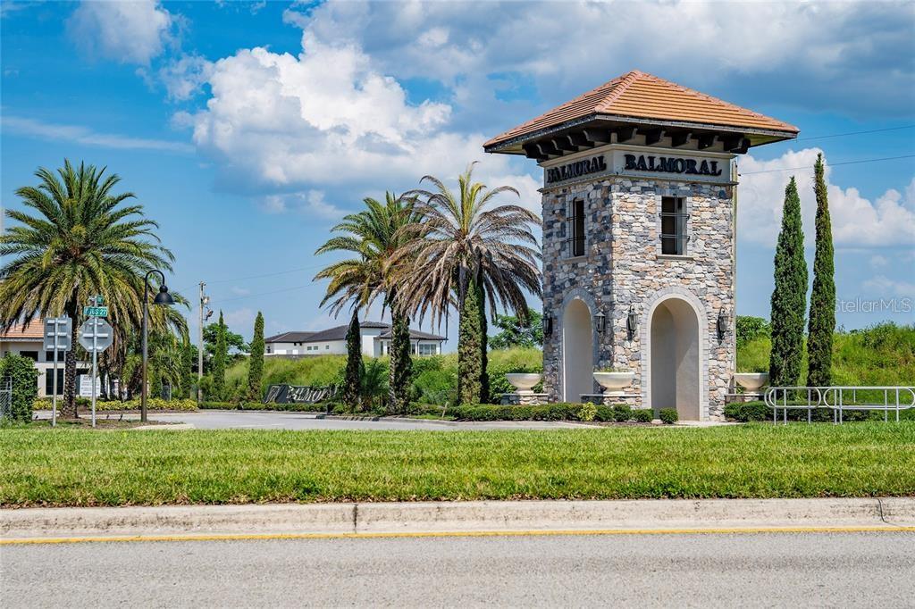 A stone entrance tower with a tiled roof stands beside palm trees and landscaping — 162 KENNY BOULEVARD, HAINES CITY, FL