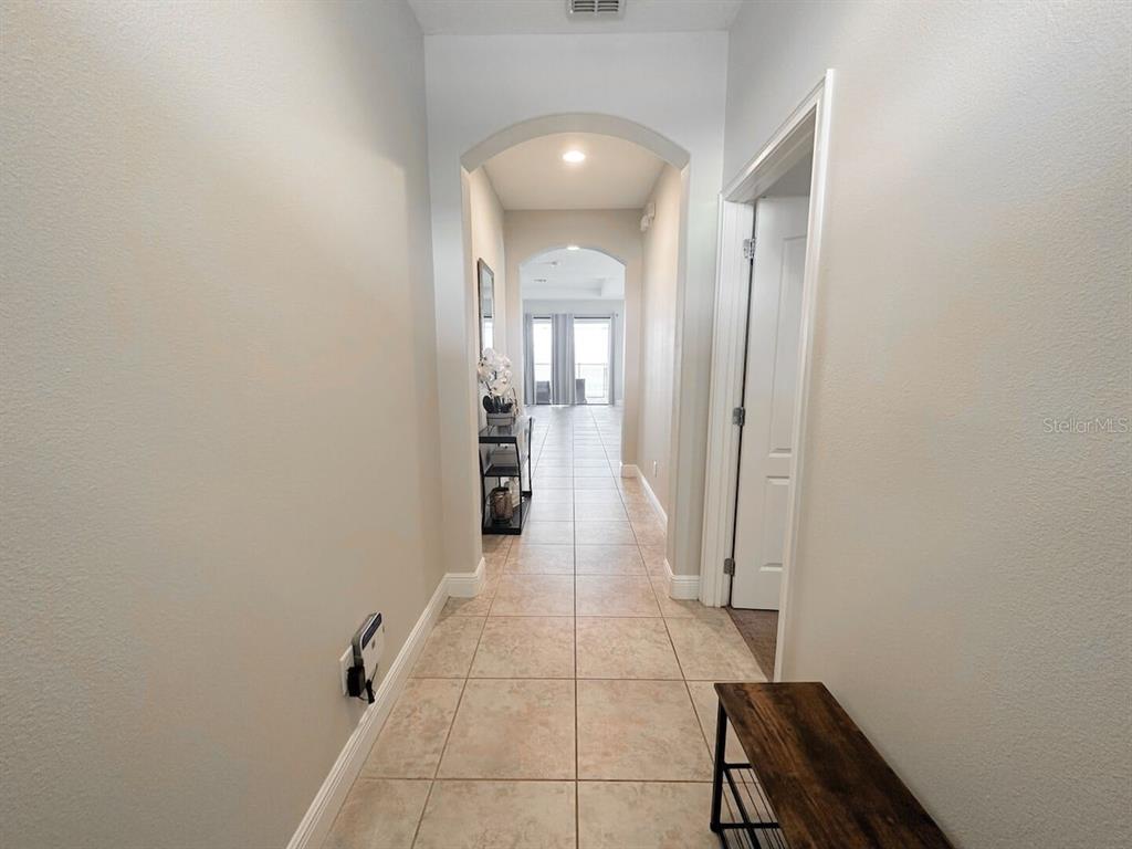 A tiled hallway features arched transitions leading toward a bright room with sliding glass doors — 162 KENNY BOULEVARD, HAINES CITY, FL