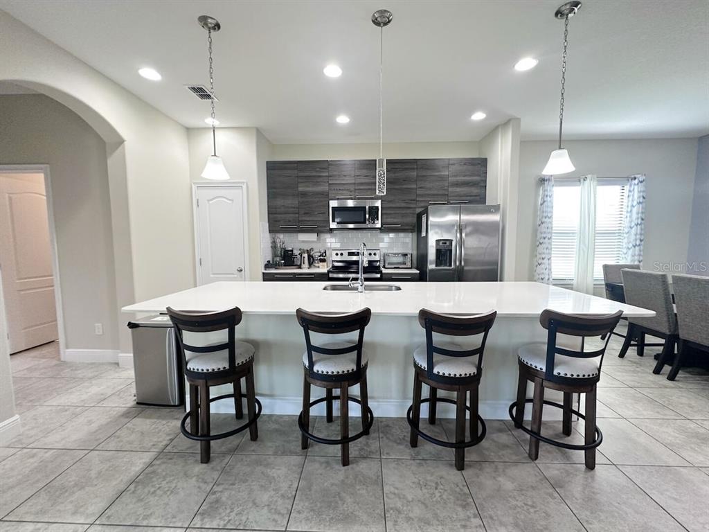 A kitchen features a large white island with four bar stools and dark wood cabinetry — 162 KENNY BOULEVARD, HAINES CITY, FL