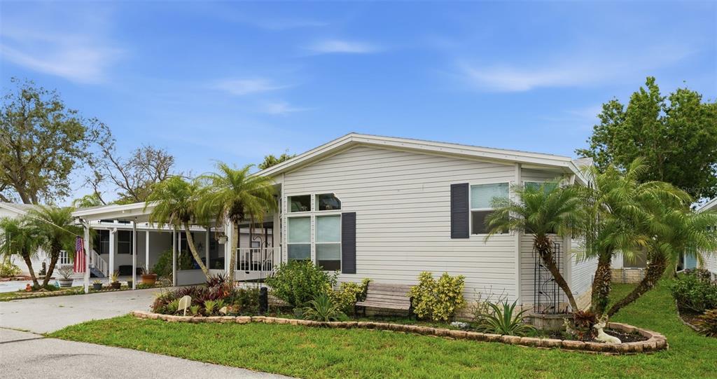 A light-colored manufactured home features a carport, a front porch, and a landscaped yard — 324 CYPRESS RUN COURT, NORTH PORT, FL