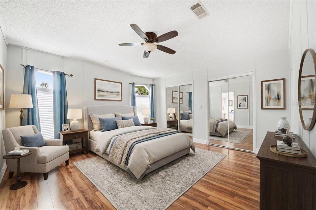 A bedroom features a bed, armchair, mirrored closet doors, and wood-look flooring — 324 CYPRESS RUN COURT, NORTH PORT, FL