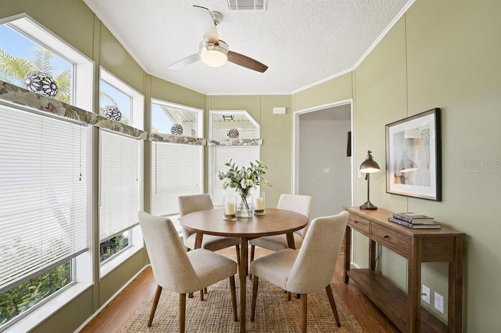 A dining area with a round wooden table, four chairs, and large windows — 324 CYPRESS RUN COURT, NORTH PORT, FL