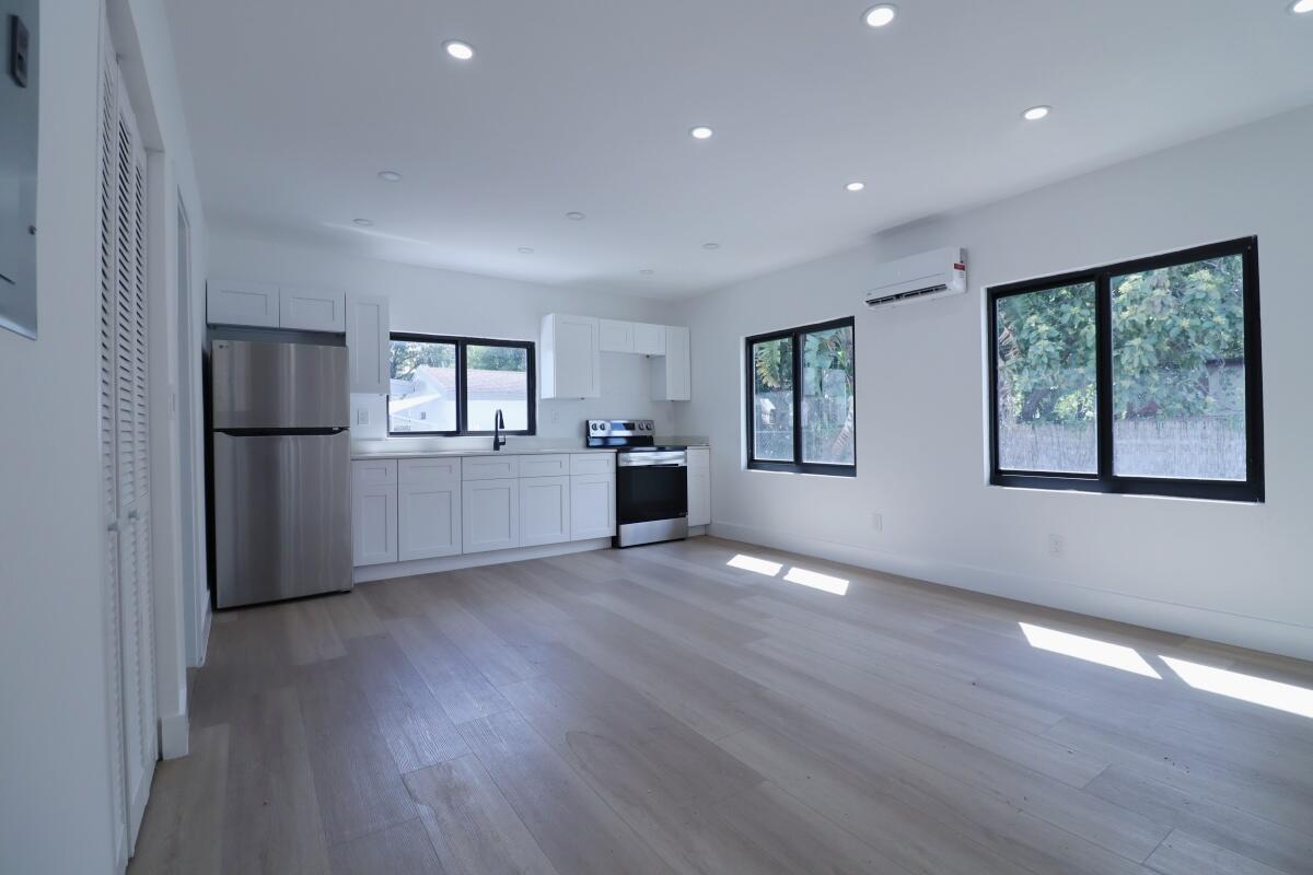 A modern kitchen with white cabinets, stainless steel appliances, and light wood flooring — 3040 NW 13th Avenue # 2, Miami FL 33142, MIAMI, FL