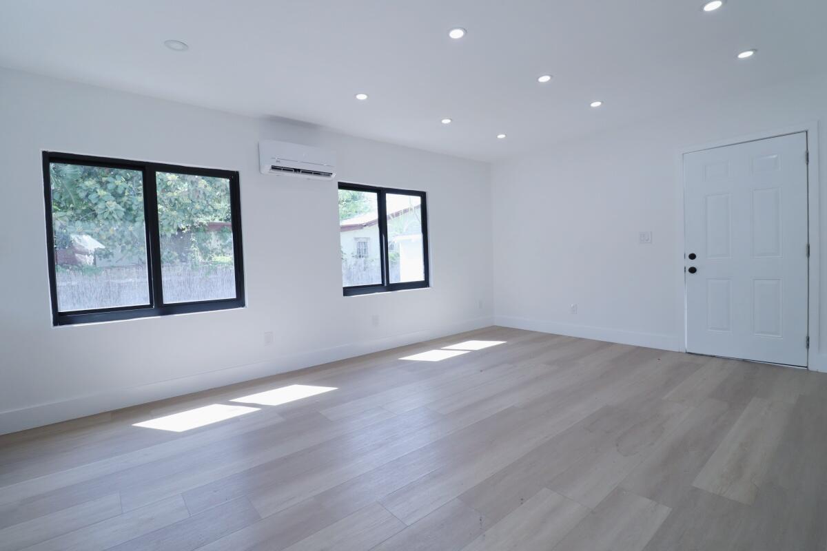 An empty room with white walls, light wood flooring, recessed lighting, and black-framed windows — 3040 NW 13th Avenue # 2, Miami FL 33142, MIAMI, FL