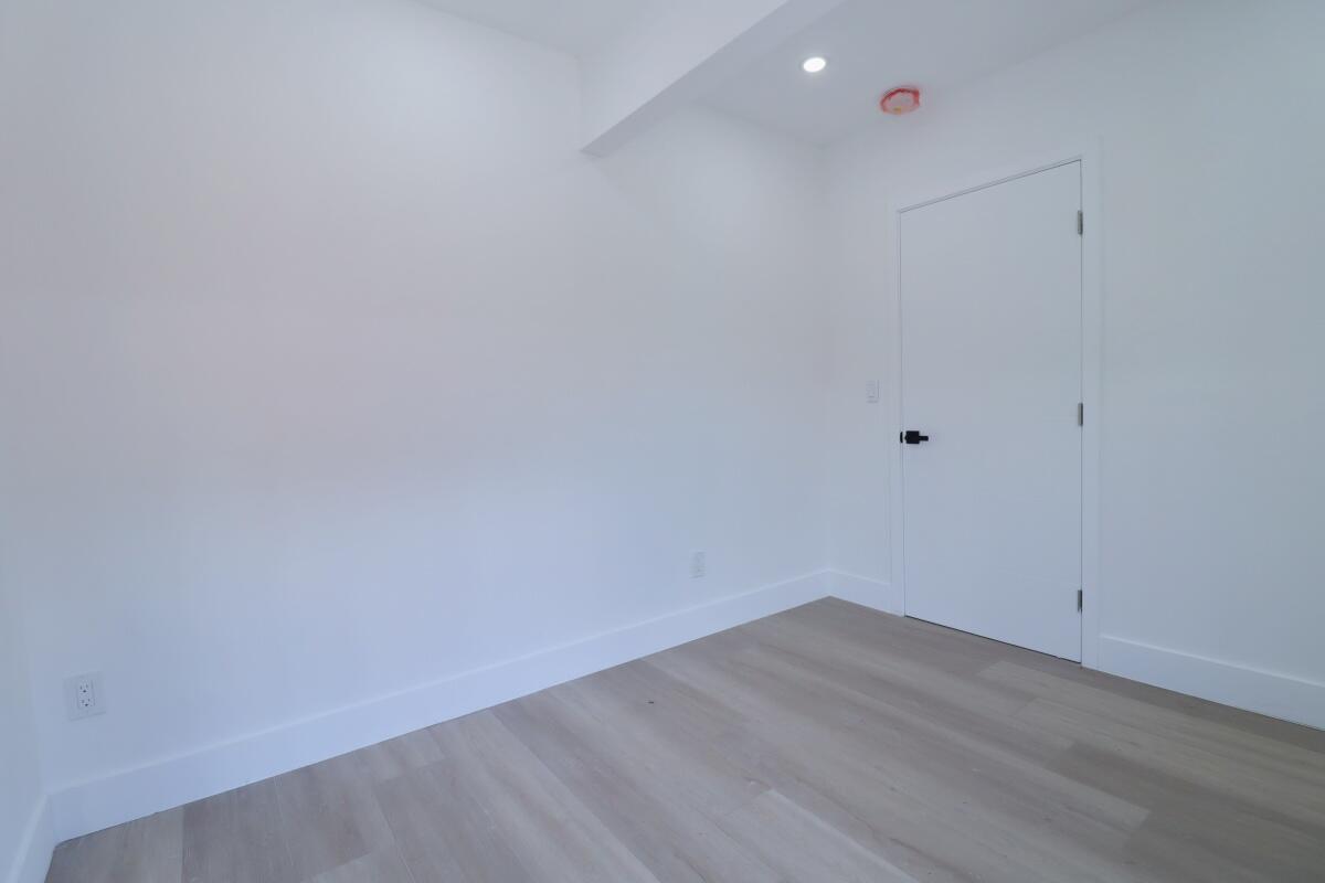 An empty room with white walls, light wood flooring, and a single white door — 3040 NW 13th Avenue # 2, Miami FL 33142, MIAMI, FL