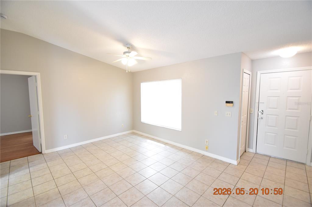An empty room features light-colored tile flooring, a ceiling fan, and a white front door — 12116 FELDWOOD CREEK LANE, RIVERVIEW, FL