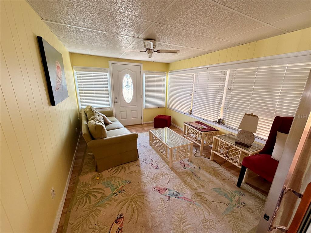 A sunroom features yellow paneled walls, a ceiling fan, a sofa, and a patterned rug — 6363 KILEPA COURT, NORTH PORT, FL