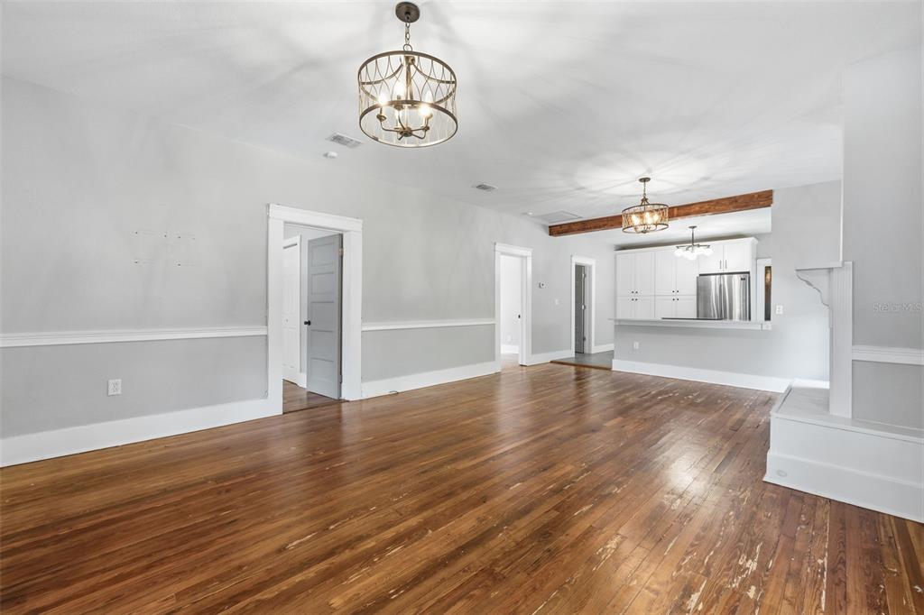 An open-concept living area features hardwood floors, white wainscoting, and two hanging light fixtures — 236 W NORTH STREET, TAMPA, FL