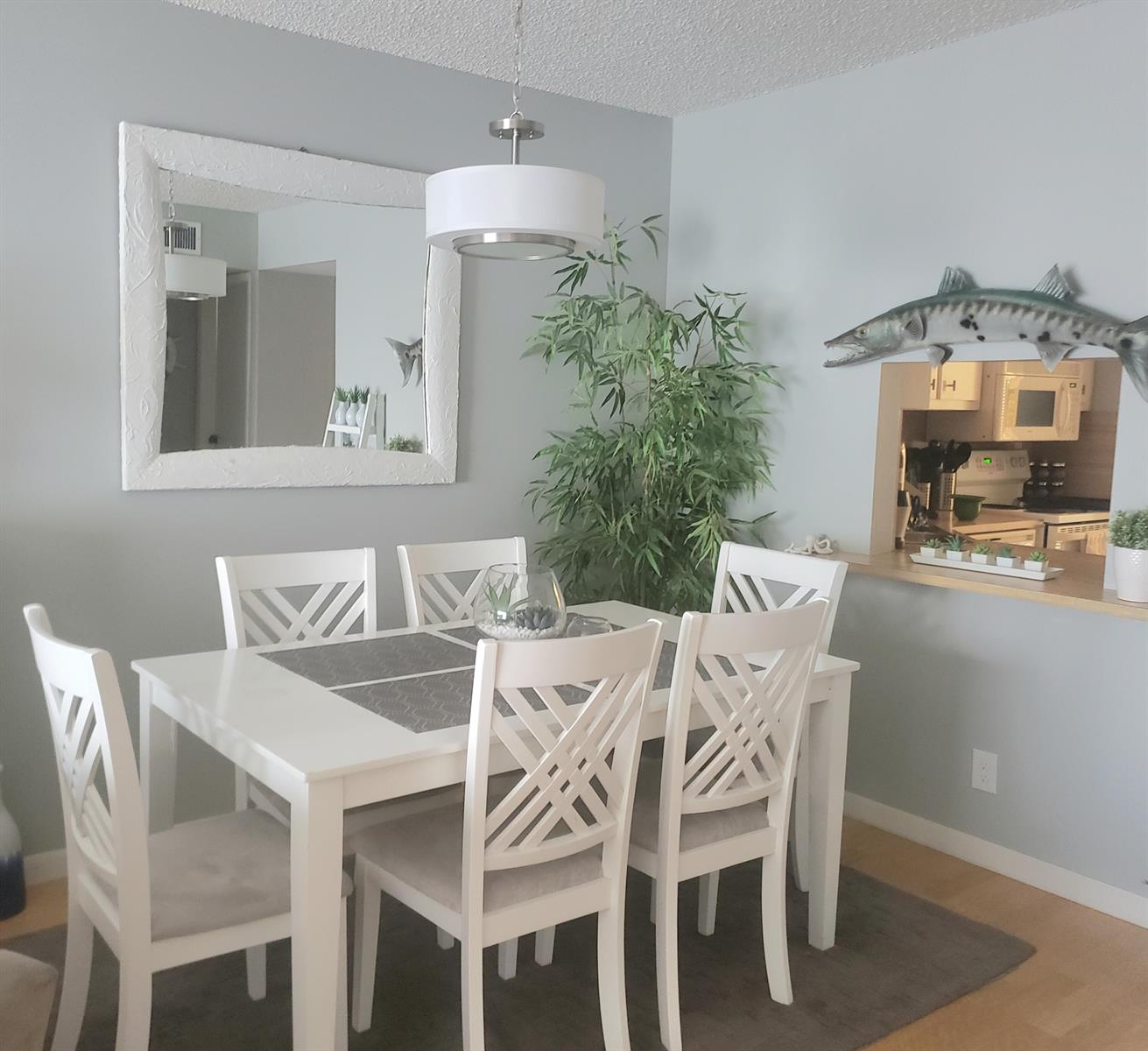 A dining room with a white table, six chairs, a large mirror, and a fish mount — 285 SE 10th Street # 8a, Deerfield Beach FL 33441, DEERFIELD BEACH, FL