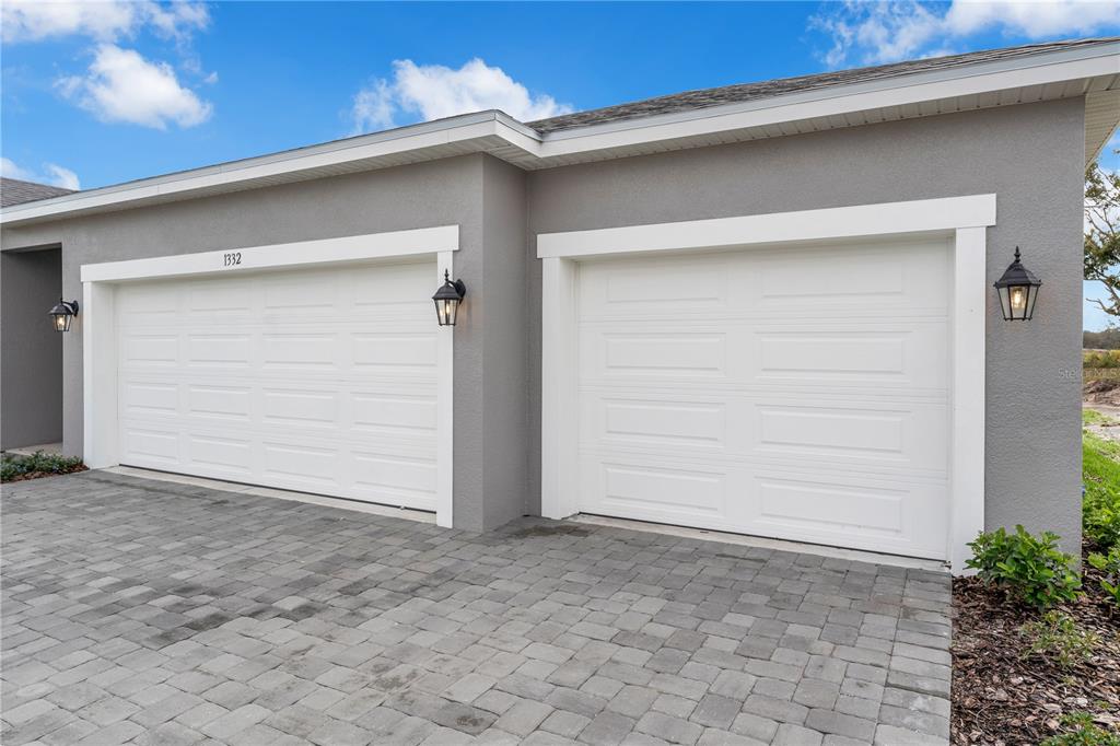 A gray house exterior features two white garage doors and a paved driveway — 1012 BANFF DRIVE NE, PALM BAY, FL