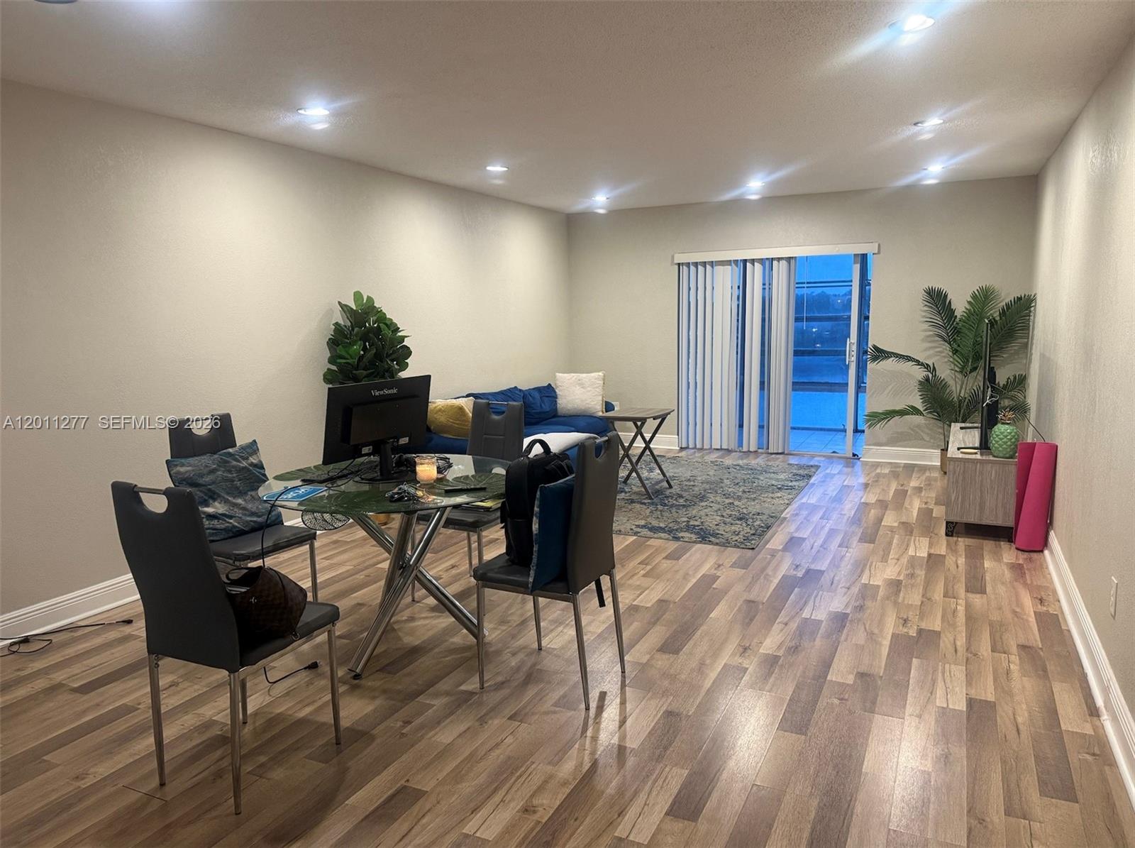 A living and dining area features wood-look flooring, recessed lighting, and a sliding glass door — 879 NE 195th St # 425, Miami FL 33179, MIAMI, FL