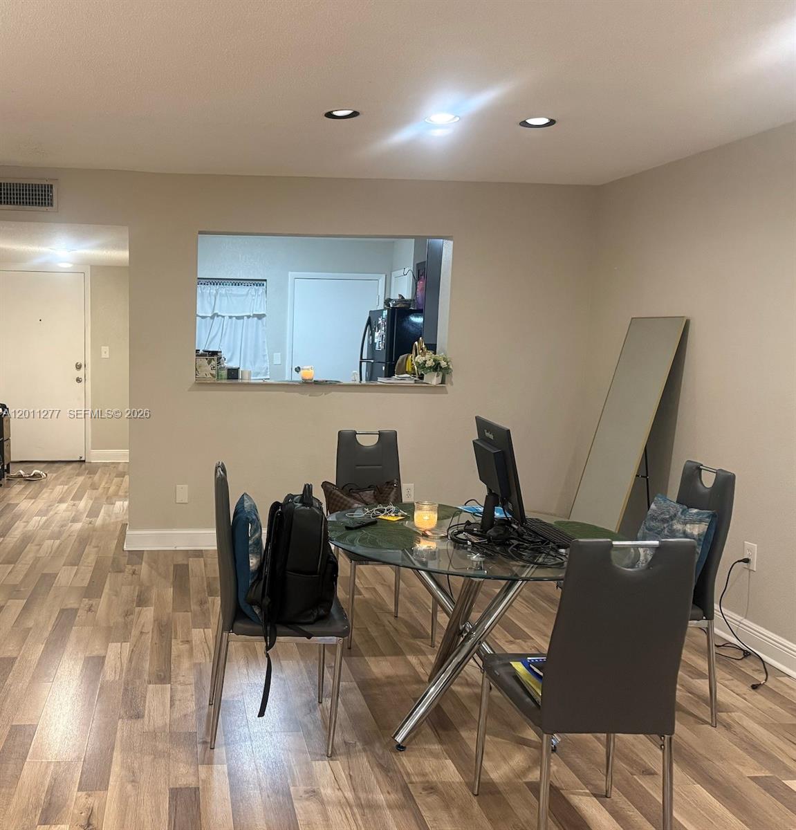 A dining area features a glass table, four grey chairs, and a kitchen pass-through window — 879 NE 195th St # 425, Miami FL 33179, MIAMI, FL