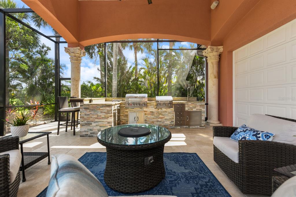 A covered outdoor patio features a stone kitchen, a fire pit, and decorative columns — 4409 CREWS COURT, PORT CHARLOTTE, FL