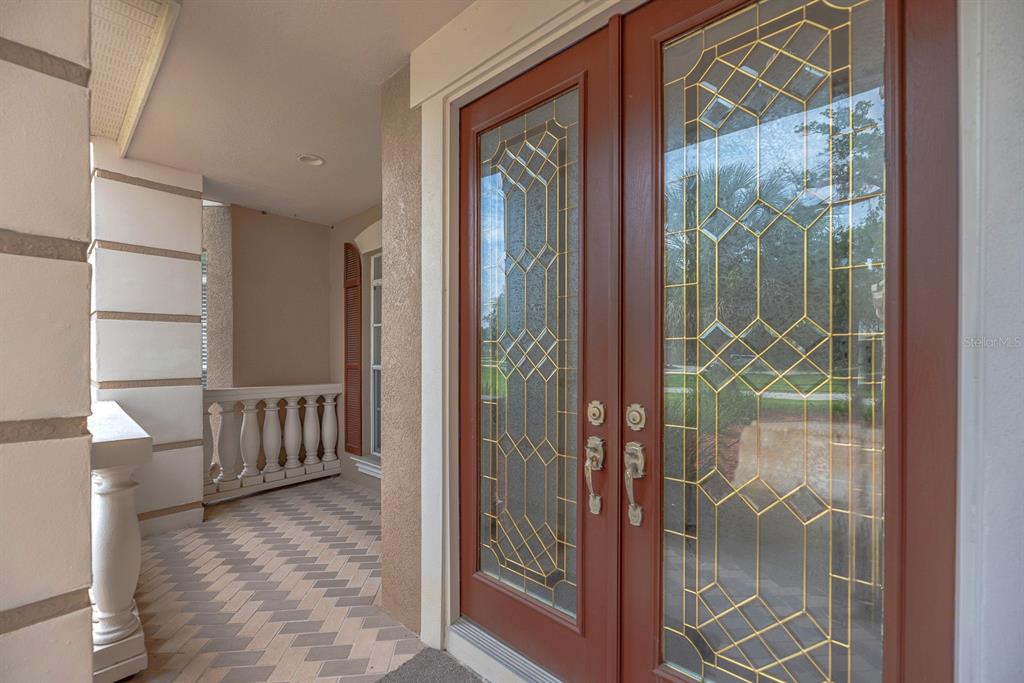 A covered porch features a herringbone-patterned floor and double doors with decorative leaded glass — 8805 CROSS LANDING LANE, RIVERVIEW, FL
