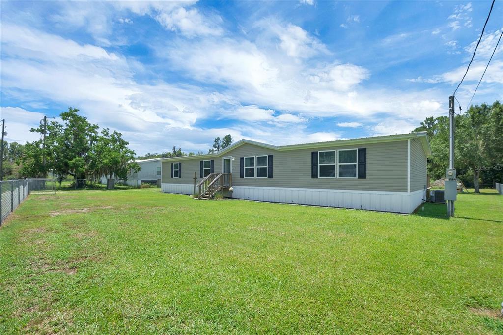 A single-story manufactured home with light-colored siding sits on a large, grassy lot — 4237 COYOTE TRAIL, POLK CITY, FL