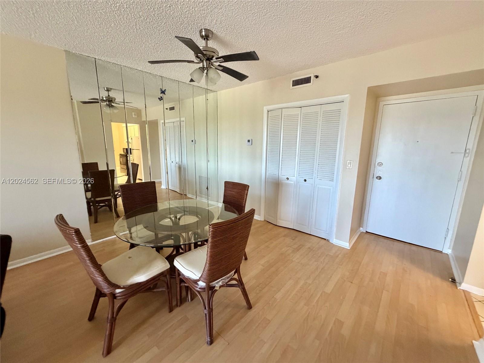 A dining area features a glass table, wicker chairs, mirrored walls, and light wood flooring — 4001 Hillcrest Dr # 609, Hollywood FL 33021, HOLLYWOOD, FL