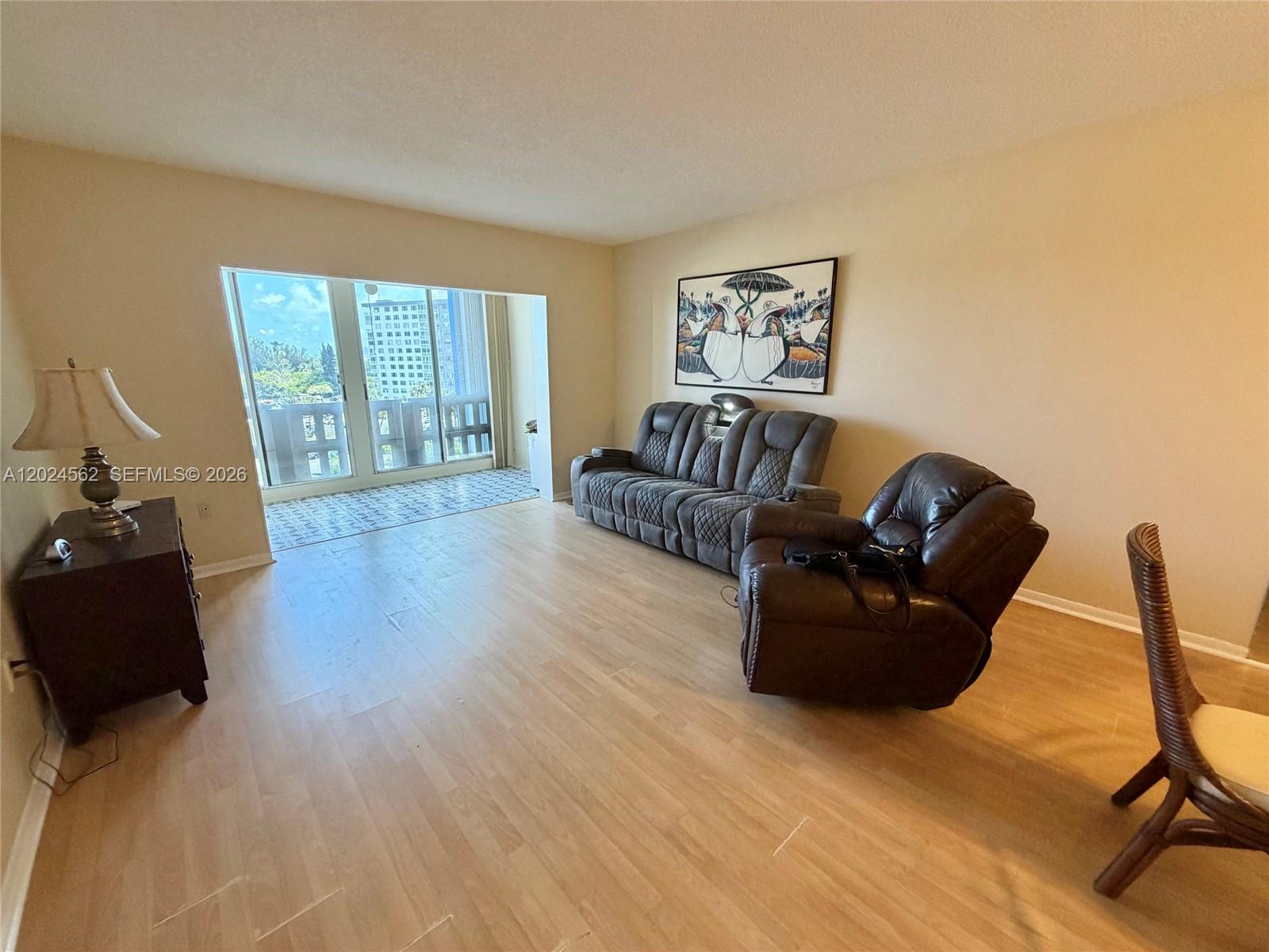 A living room features light wood flooring, a gray sofa, a recliner, and a balcony — 4001 Hillcrest Dr # 609, Hollywood FL 33021, HOLLYWOOD, FL