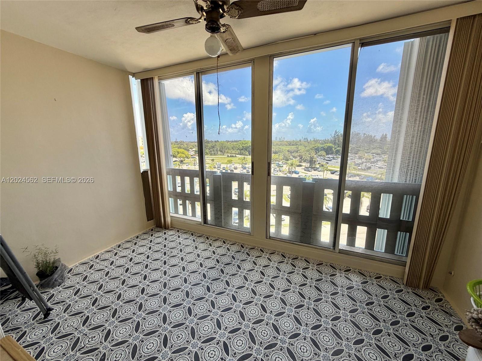 A sunroom features patterned tile flooring, a ceiling fan, and large windows overlooking a parking lot — 4001 Hillcrest Dr # 609, Hollywood FL 33021, HOLLYWOOD, FL