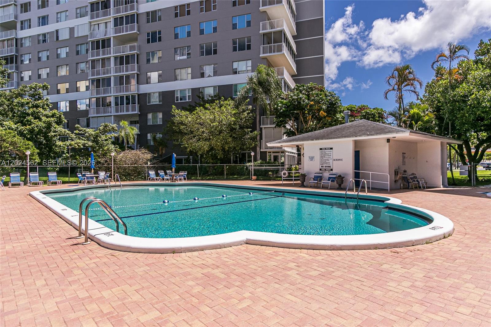 A swimming pool with a surrounding patio sits in front of a multi-story apartment building — 4001 Hillcrest Dr # 609, Hollywood FL 33021, HOLLYWOOD, FL