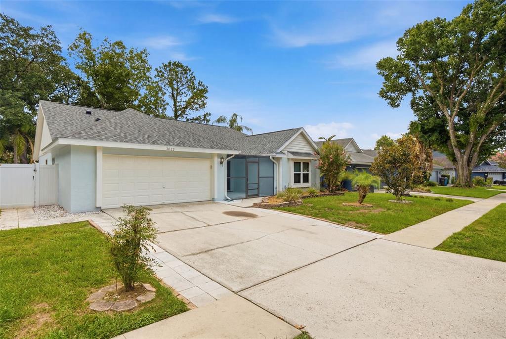 A light blue single-story house with a two-car garage and a screened-in front entryway — 2023 DARLINGTON OAK DRIVE, SEFFNER, FL