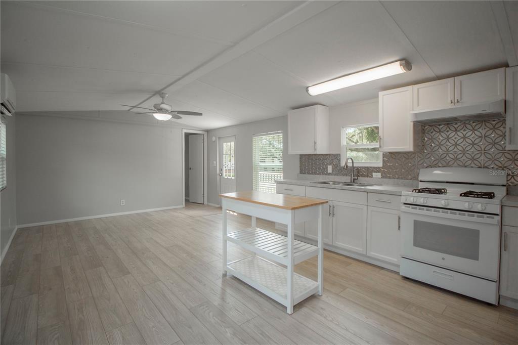 A kitchen with white cabinets, a portable island, and light wood-look flooring — 28 SHADY LANE S, PALM COAST, FL