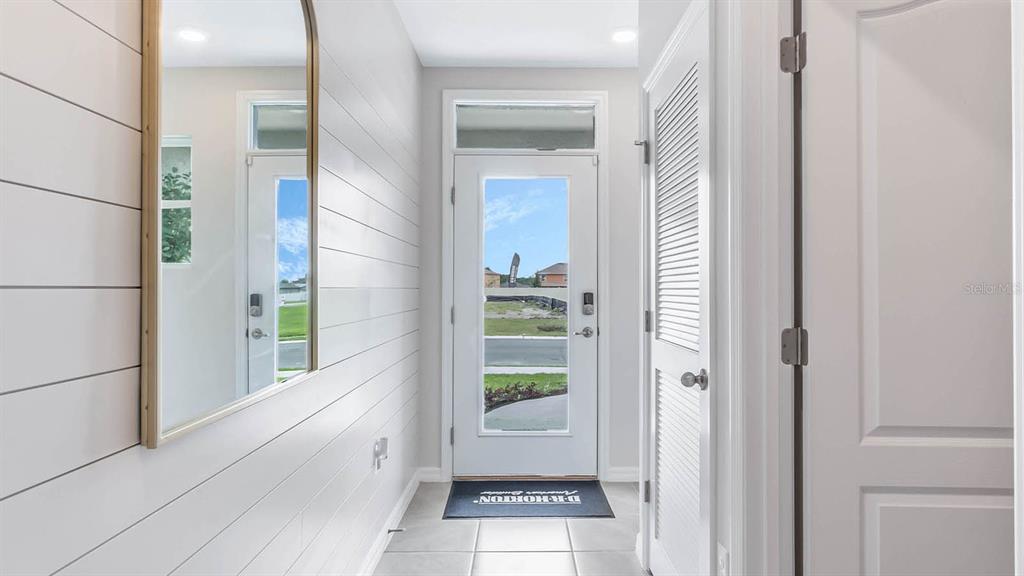 A bright entryway features white shiplap walls, a tall arched mirror, and a glass-paneled door — 3018 VICEROY COURT, POINCIANA, FL