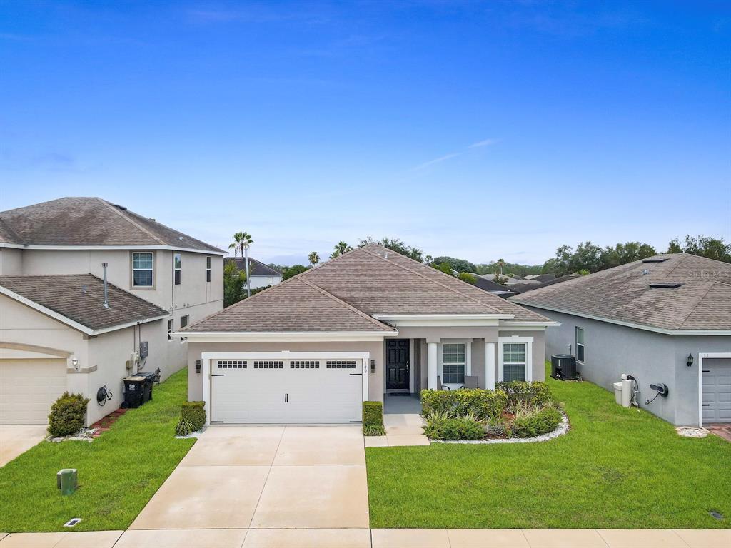 A single-story suburban house with a two-car garage and a landscaped front yard — 149 BELLA VERANO WAY, DAVENPORT, FL