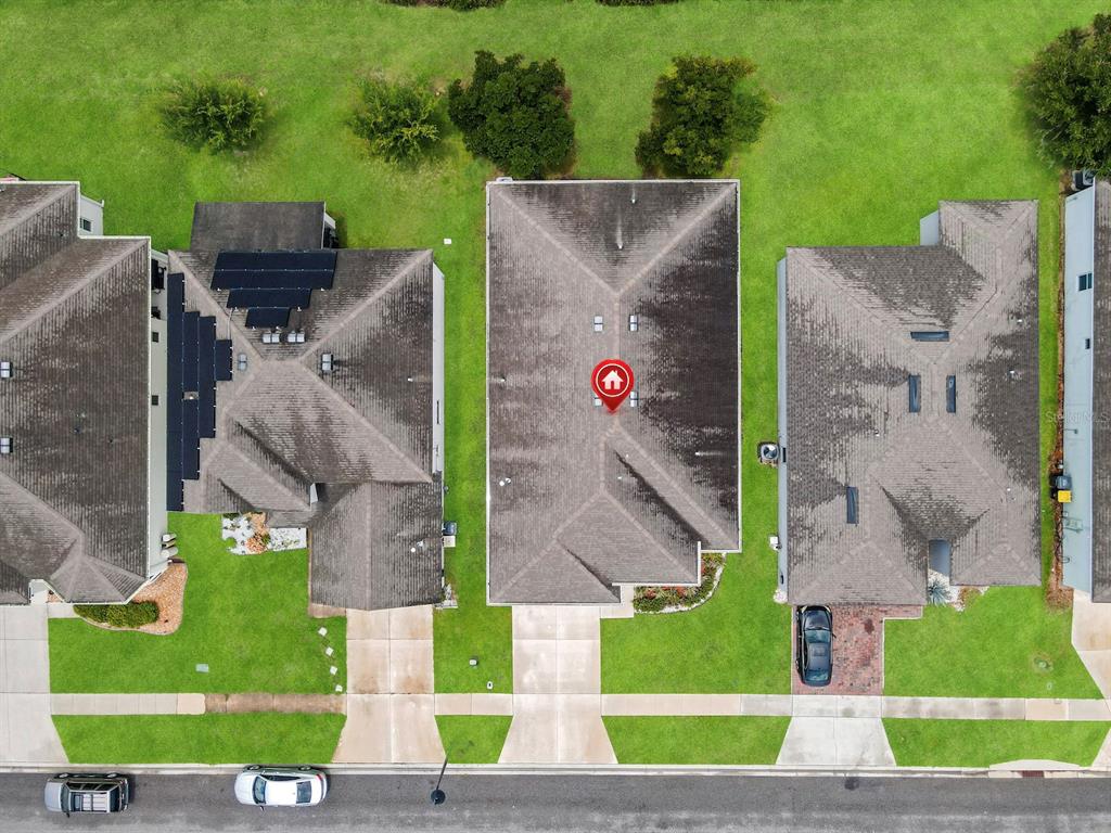An aerial view shows three suburban houses with shingled roofs and driveways from above — 149 BELLA VERANO WAY, DAVENPORT, FL