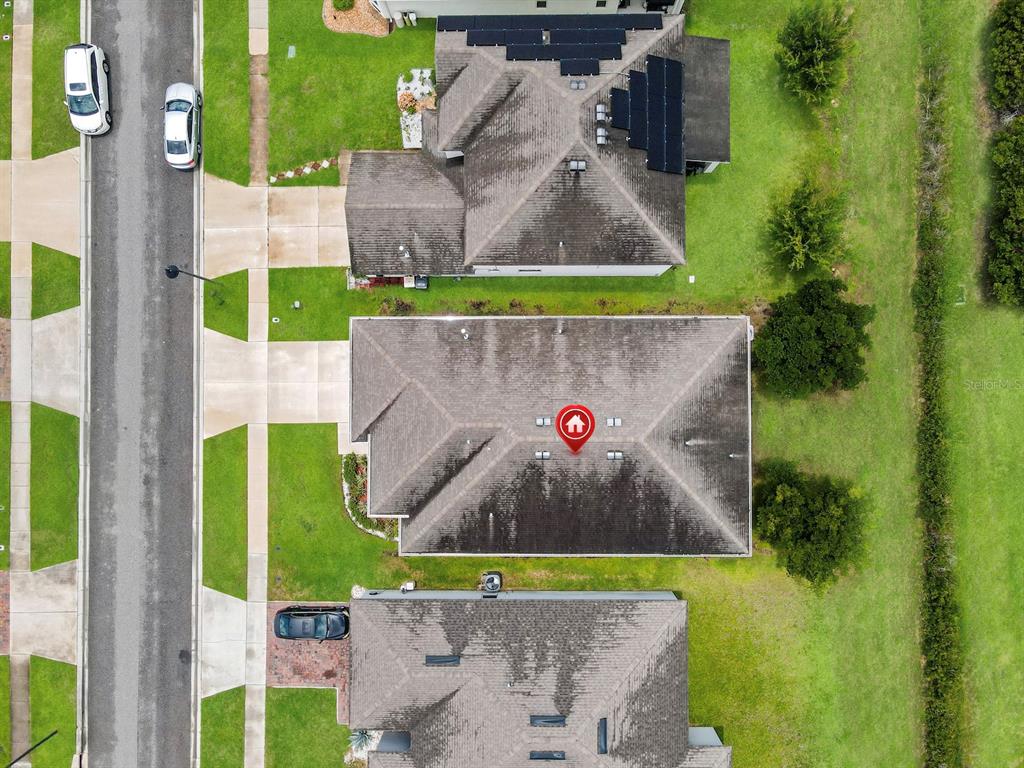 An aerial view shows three suburban houses with shingled roofs and driveways along a street — 149 BELLA VERANO WAY, DAVENPORT, FL
