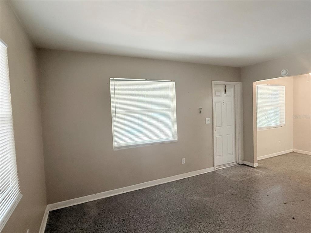 A room with gray walls, carpeted flooring, two windows with blinds, and a white door — 1304 BROWNING STREET, CLEARWATER, FL