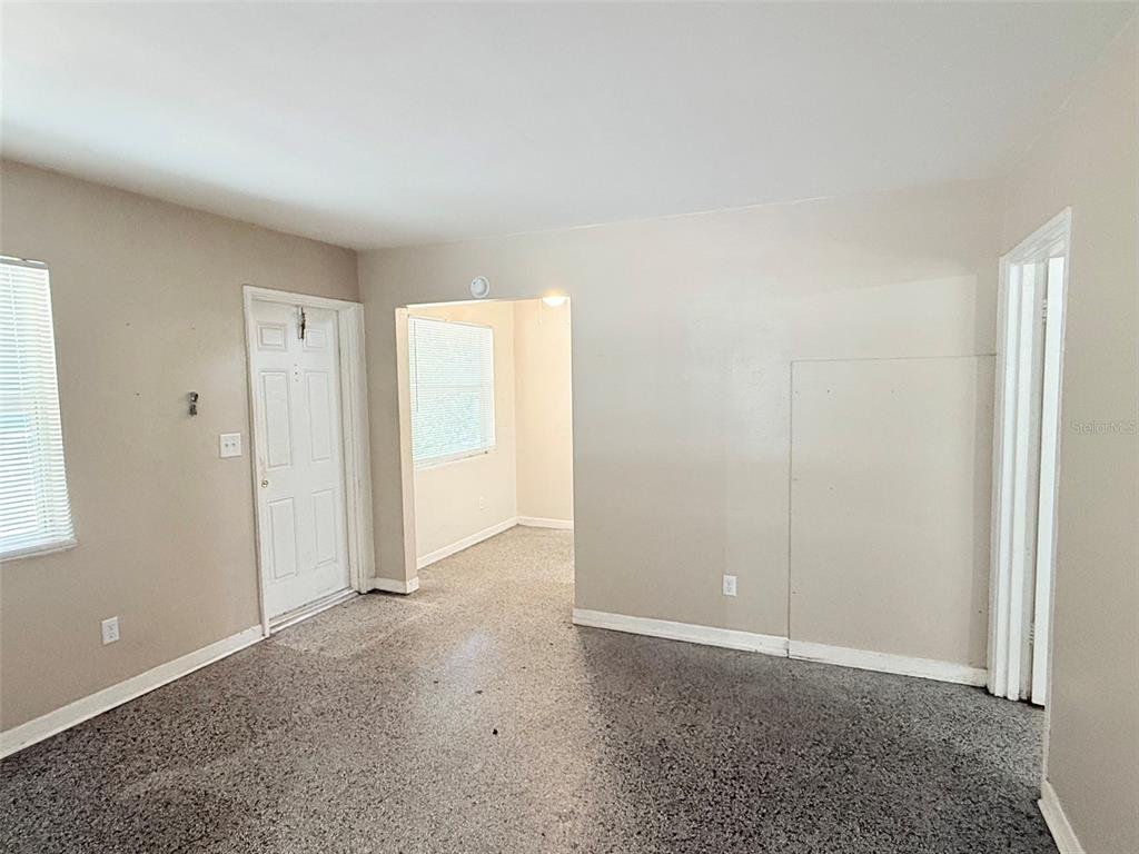 An interior view of a room with speckled flooring, beige walls, and a doorway — 1304 BROWNING STREET, CLEARWATER, FL