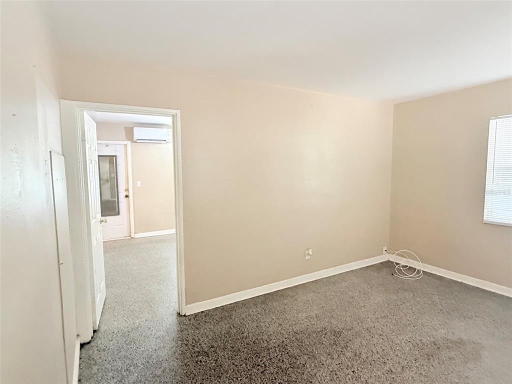 An interior view shows a room with beige walls, a speckled floor, and a doorway — 1304 BROWNING STREET, CLEARWATER, FL