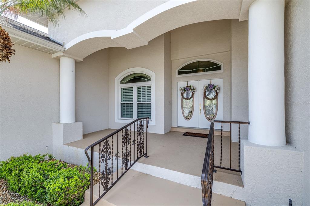 A covered front porch with white columns, a double door entrance, and decorative metal railings — 6758 HUNTINGTON HILLS BOULEVARD, LAKELAND, FL