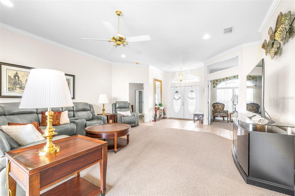 A living room features gray leather seating, a round wooden coffee table, and carpeted floors — 6758 HUNTINGTON HILLS BOULEVARD, LAKELAND, FL