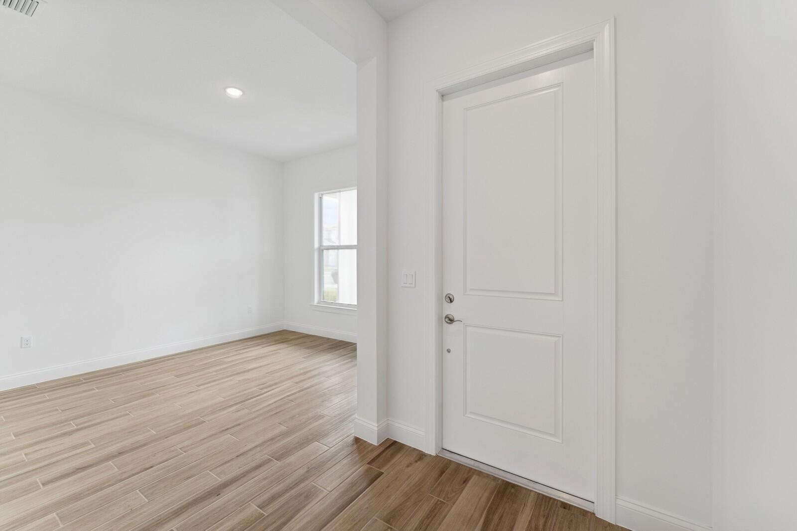 A white door stands next to an open doorway leading to a room with wood-look flooring — 6799 SE Lost Pine Drive, Stuart FL 34997, STUART, FL