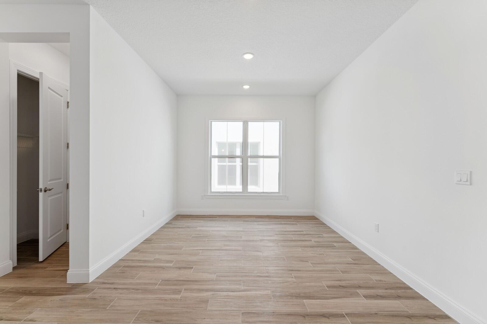 An empty room with white walls, wood-look tile flooring, a window, and a closet door — 6799 SE Lost Pine Drive, Stuart FL 34997, STUART, FL