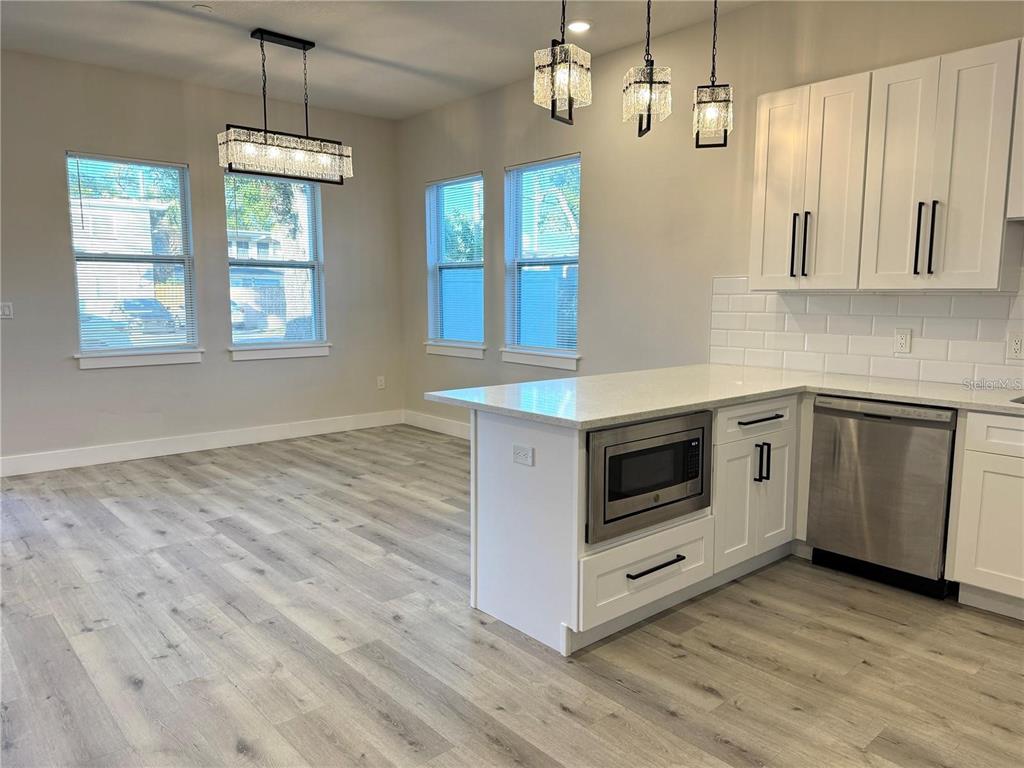 A kitchen and dining area feature white cabinets, stainless steel appliances, and light wood flooring — 1039 53RD AVENUE N, ST PETERSBURG, FL