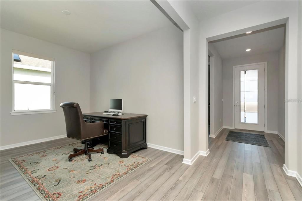 A home office with a desk and chair sits next to an entryway with a door — 1991 SPRING SHOWER CIRCLE, KISSIMMEE, FL